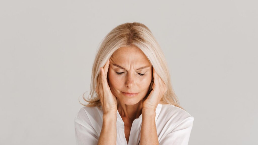 femme de 45 ans, blonde, qui se tient la tête dans les mains